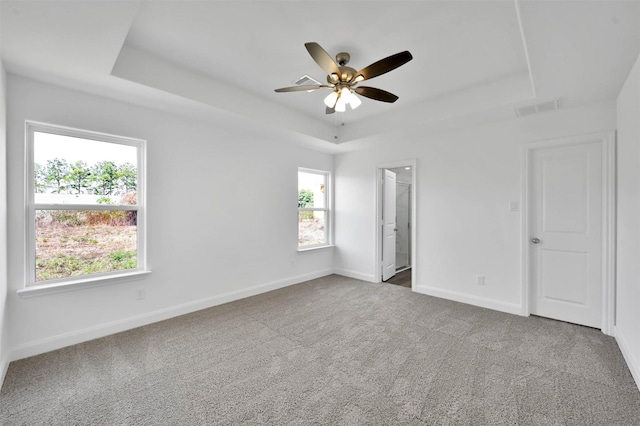 carpeted spare room featuring a raised ceiling and ceiling fan