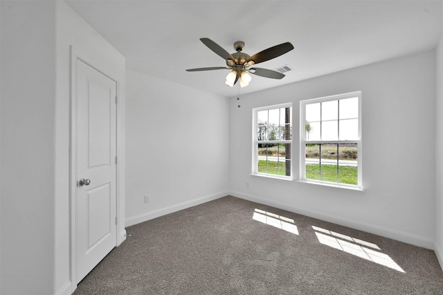 spare room featuring ceiling fan and dark carpet