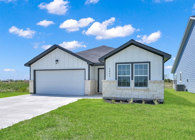 view of front of home with central AC, a front lawn, and a garage