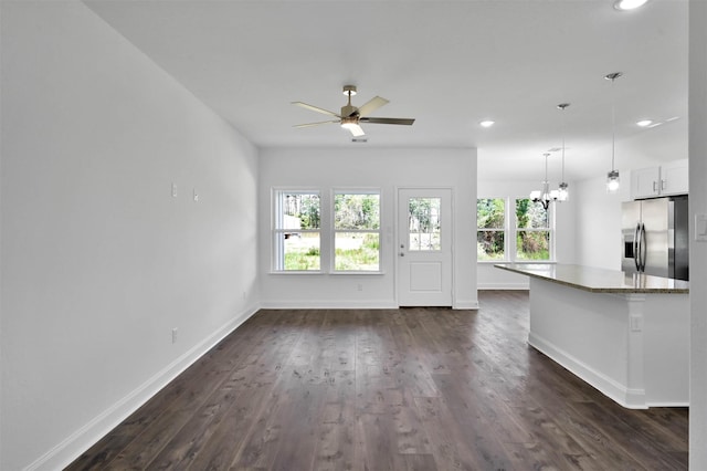 kitchen with dark wood-type flooring, white cabinets, ceiling fan with notable chandelier, light stone countertops, and stainless steel fridge with ice dispenser