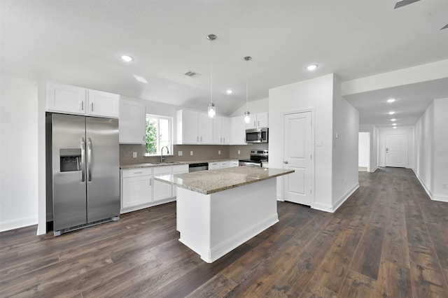 kitchen with white cabinets, hanging light fixtures, a kitchen island, and stainless steel appliances