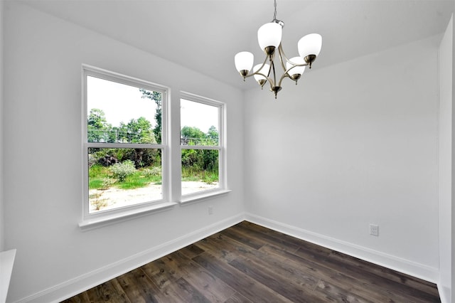 empty room with dark hardwood / wood-style flooring and a chandelier