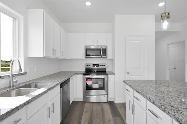 kitchen featuring appliances with stainless steel finishes, light stone counters, sink, dark hardwood / wood-style floors, and white cabinetry