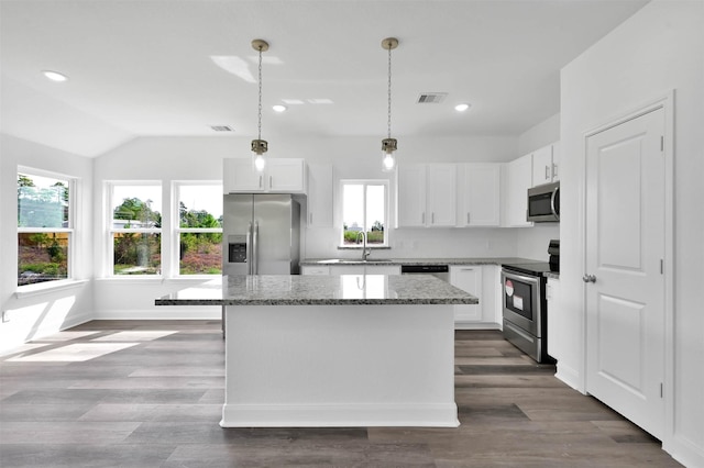 kitchen featuring white cabinets, stainless steel appliances, a kitchen island, and a wealth of natural light