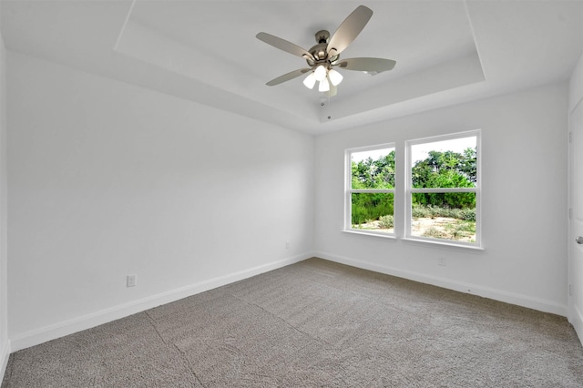 carpeted empty room with ceiling fan and a tray ceiling