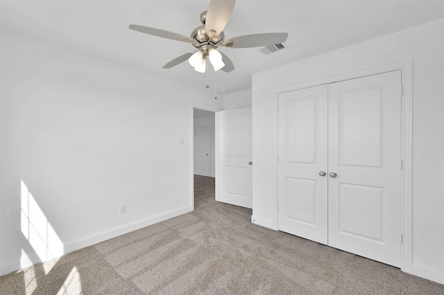 unfurnished bedroom featuring a closet, light colored carpet, and ceiling fan