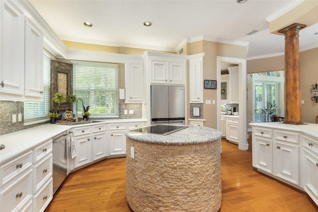 kitchen featuring white cabinets, appliances with stainless steel finishes, plenty of natural light, a kitchen island, and decorative columns