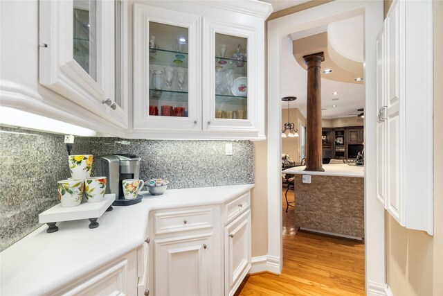 bar with white cabinets, ceiling fan, light hardwood / wood-style flooring, and tasteful backsplash