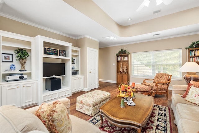 living room featuring a raised ceiling, dark hardwood / wood-style floors, ceiling fan, built in shelves, and ornamental molding