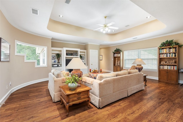 living room featuring dark hardwood / wood-style floors, a healthy amount of sunlight, ceiling fan, and a tray ceiling