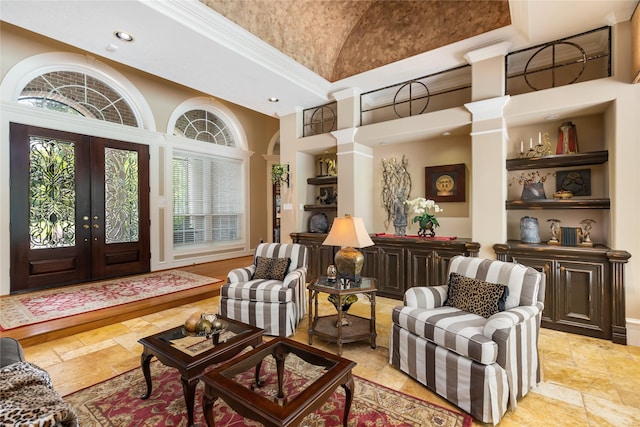 interior space with french doors, decorative columns, high vaulted ceiling, and crown molding