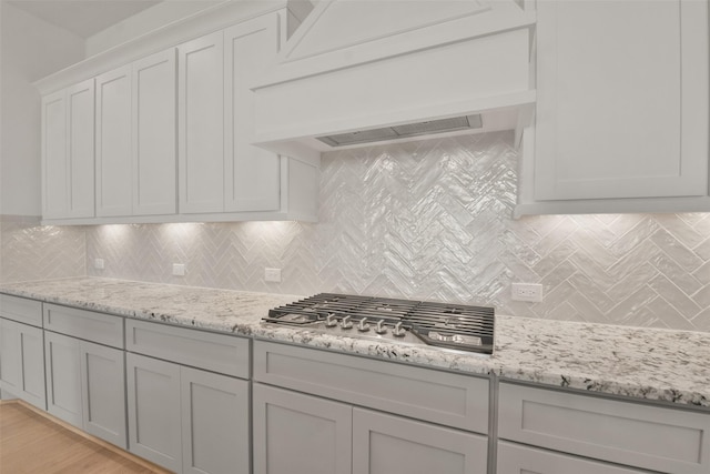 13318 Pine Lake Bnd, Tomball, TX 77375 - kitchen with light stone countertops, light hardwood / wood-style flooring, stainless steel gas stovetop, decorative backsplash, and custom range hood