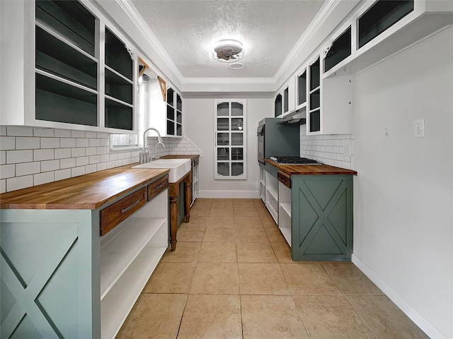 kitchen featuring a textured ceiling, light tile patterned floors, wooden counters, crown molding, and sink