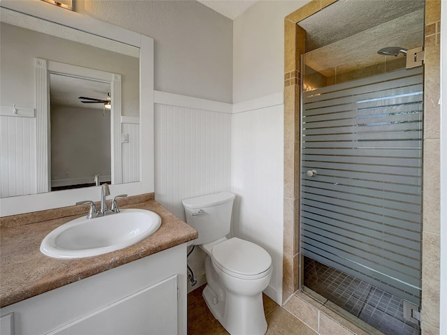 bathroom with toilet, vanity, a shower with shower door, and ceiling fan