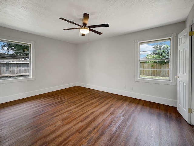 empty room with a textured ceiling, ceiling fan, and dark hardwood / wood-style floors