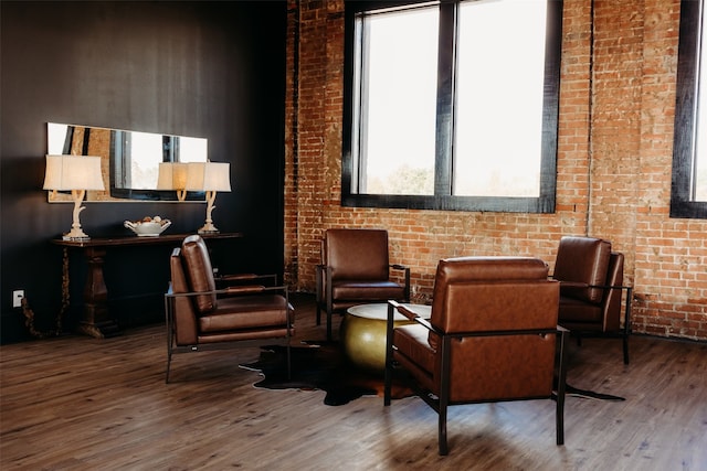 sitting room with a healthy amount of sunlight, hardwood / wood-style floors, and brick wall