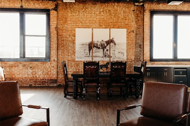 dining space with hardwood / wood-style flooring and brick wall