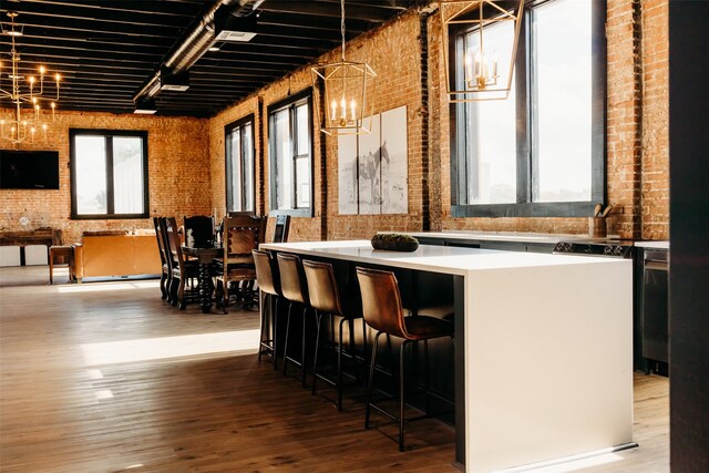 bar featuring brick wall, hardwood / wood-style floors, a chandelier, and pendant lighting