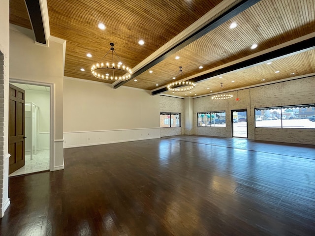 empty room featuring a notable chandelier, dark wood-type flooring, brick wall, and wooden ceiling