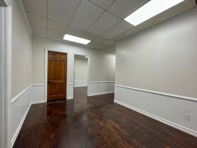 empty room featuring ornamental molding, a paneled ceiling, and dark hardwood / wood-style flooring