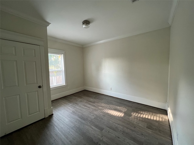 spare room with dark hardwood / wood-style flooring and crown molding