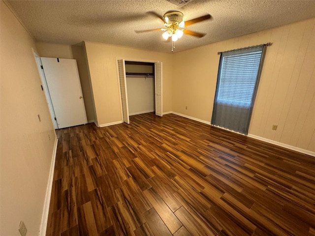 unfurnished bedroom with a closet, a textured ceiling, dark hardwood / wood-style floors, and ceiling fan