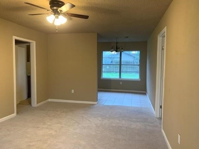 carpeted empty room with ceiling fan with notable chandelier and a textured ceiling