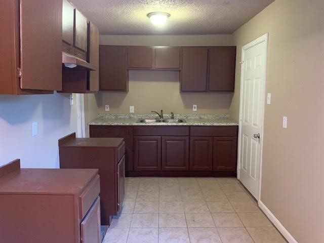 kitchen with a textured ceiling, dark brown cabinets, and sink