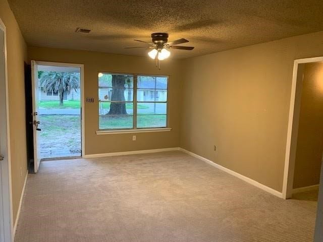 spare room featuring a textured ceiling, carpet floors, and ceiling fan