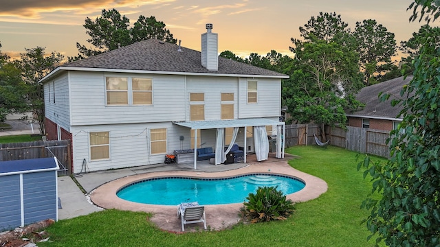 back house at dusk with a fenced in pool, a yard, and a patio