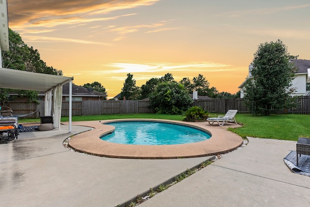 pool at dusk featuring a patio area and a lawn