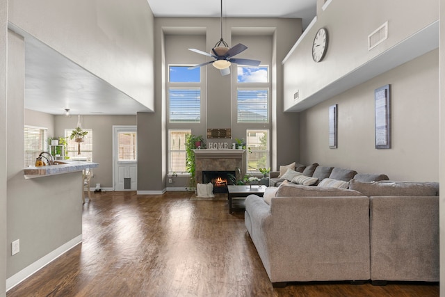 living room featuring a high ceiling, dark hardwood / wood-style flooring, ceiling fan, and sink