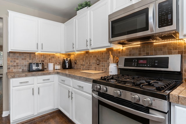 kitchen featuring white cabinets, stainless steel appliances, and tasteful backsplash