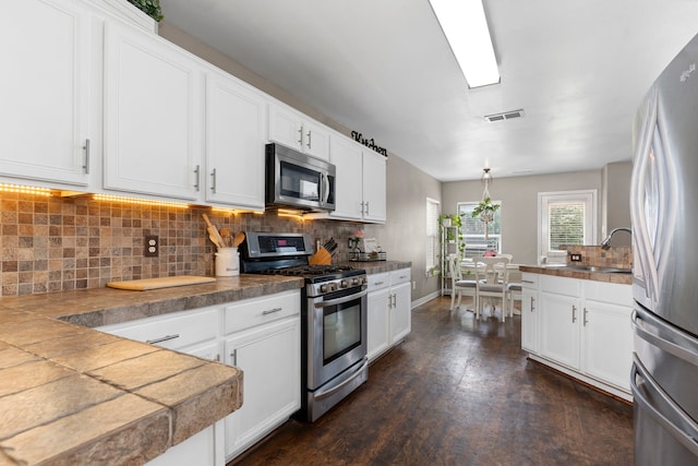 kitchen featuring appliances with stainless steel finishes, white cabinetry, tile counters, and sink