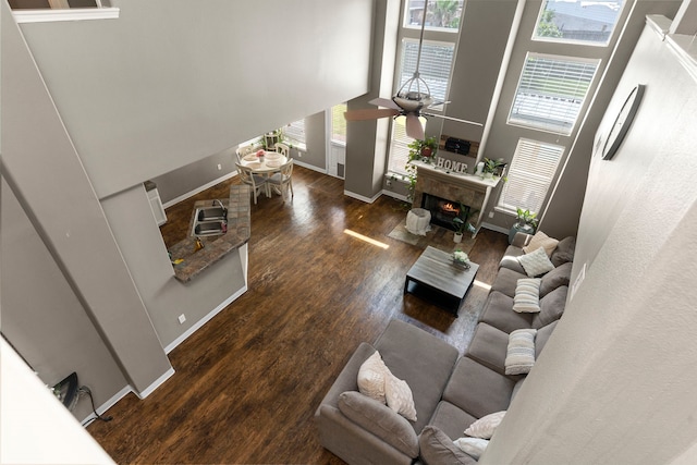 living room with a high ceiling, ceiling fan, and dark wood-type flooring