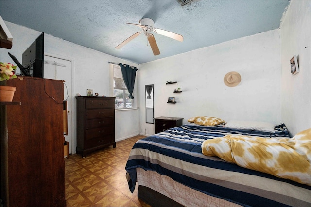 bedroom with a textured ceiling, ceiling fan, and light parquet flooring