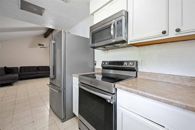 kitchen with lofted ceiling with beams, white cabinetry, light tile patterned flooring, and stainless steel appliances