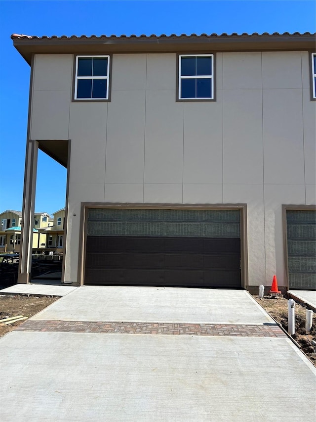 view of front of property featuring a tile roof, driveway, and an attached garage