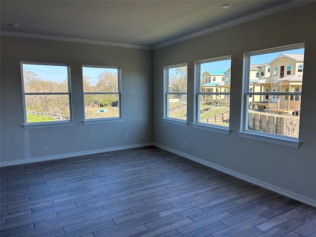 spare room with baseboards, wood finished floors, and ornamental molding