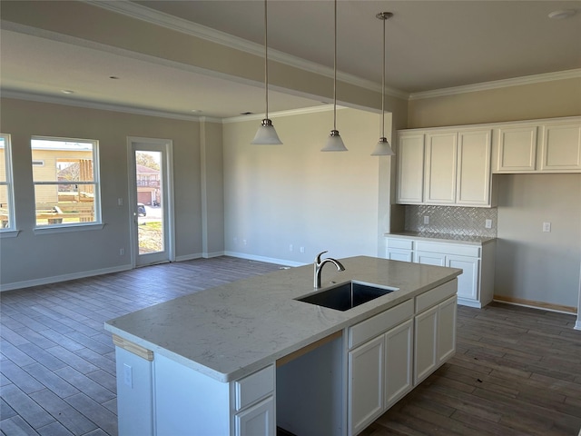 kitchen with dark wood finished floors, a sink, decorative backsplash, white cabinets, and crown molding