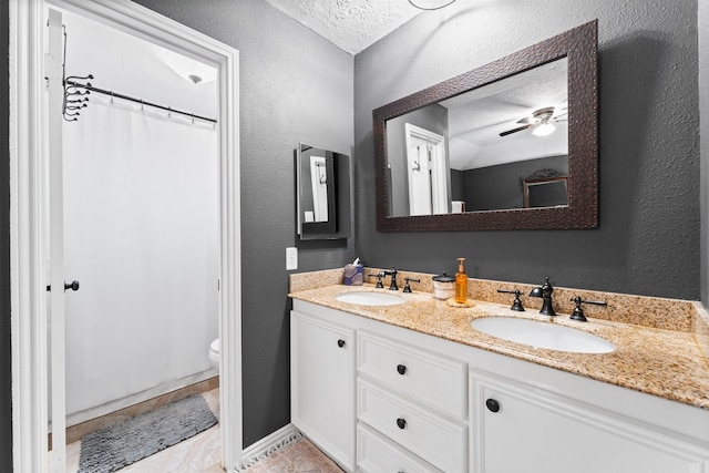 bathroom featuring vanity, toilet, curtained shower, and a textured ceiling