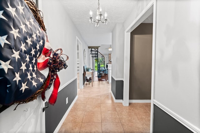 hallway featuring an inviting chandelier, light tile patterned floors, and a textured ceiling