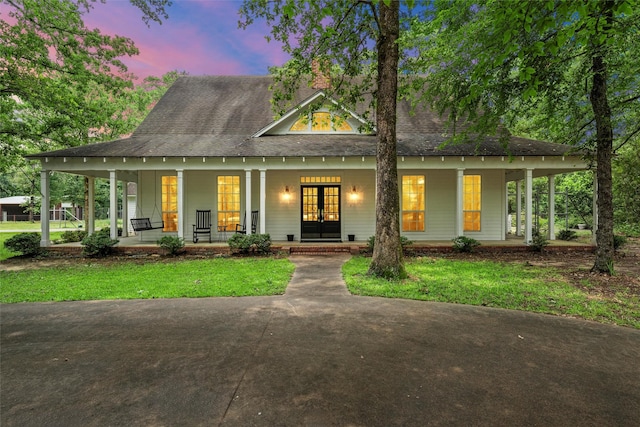 view of front of property featuring french doors, a porch, and a shingled roof