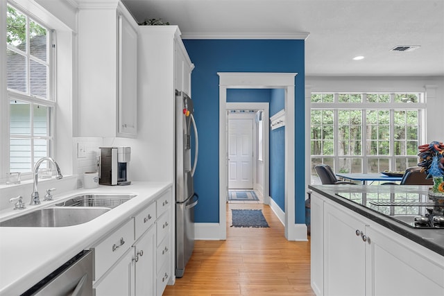 kitchen with light hardwood / wood-style floors, backsplash, white cabinetry, sink, and appliances with stainless steel finishes