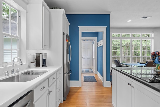 kitchen featuring visible vents, white cabinetry, stainless steel appliances, and a sink