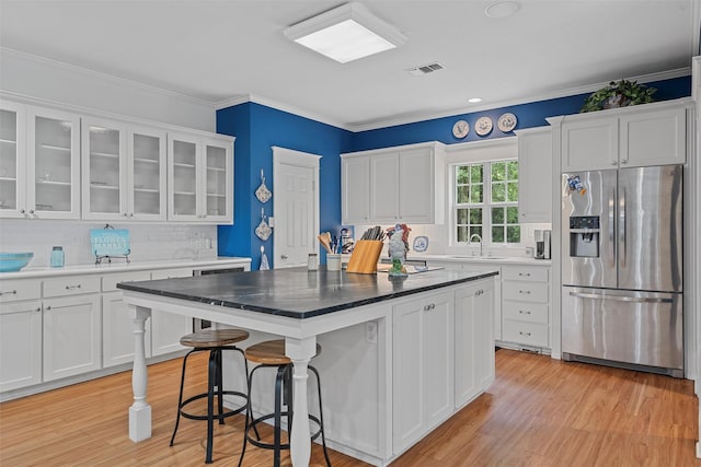 kitchen with visible vents, white cabinets, stainless steel refrigerator with ice dispenser, and ornamental molding