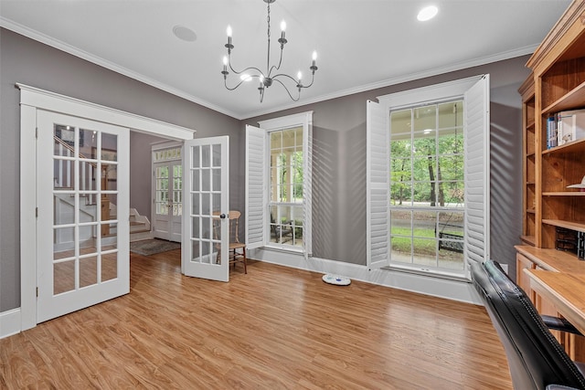 interior space with wood finished floors, plenty of natural light, french doors, crown molding, and a chandelier