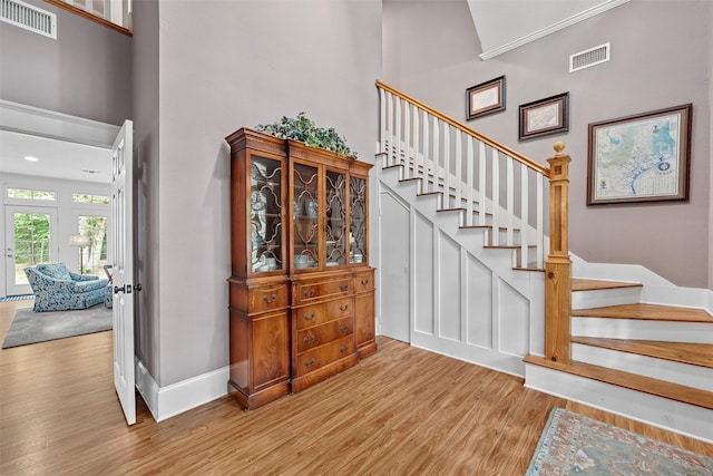 stairs with visible vents, a high ceiling, and wood finished floors