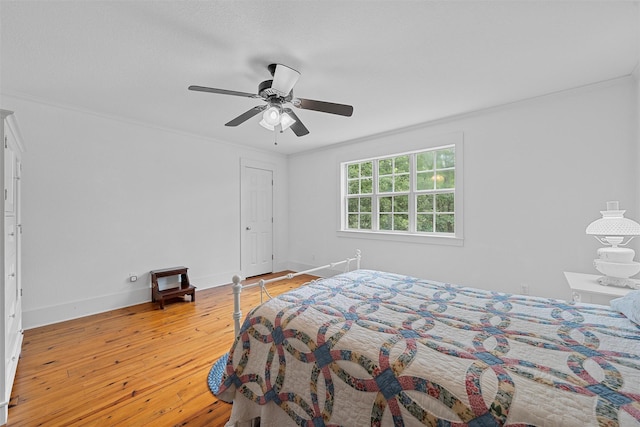 bedroom with a ceiling fan, crown molding, light wood-style floors, and baseboards