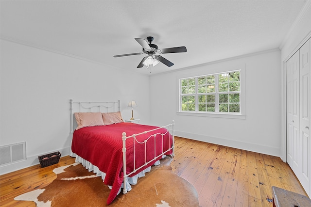 bedroom with crown molding, hardwood / wood-style flooring, a closet, and ceiling fan